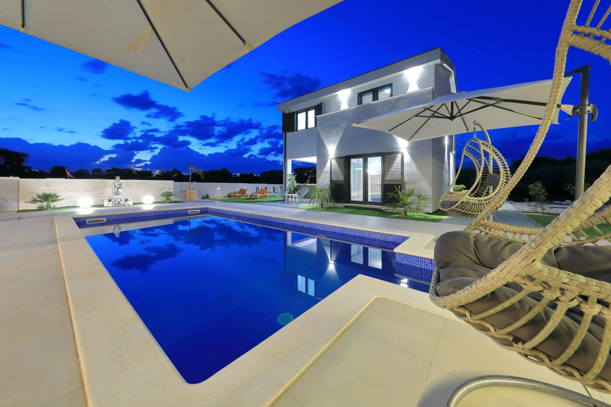 Ferienhaus Artemis mit beleuchtetem Pool in der Abenddämmerung